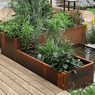 Plantekasser i cortenstål med grønne planter og vannspeil